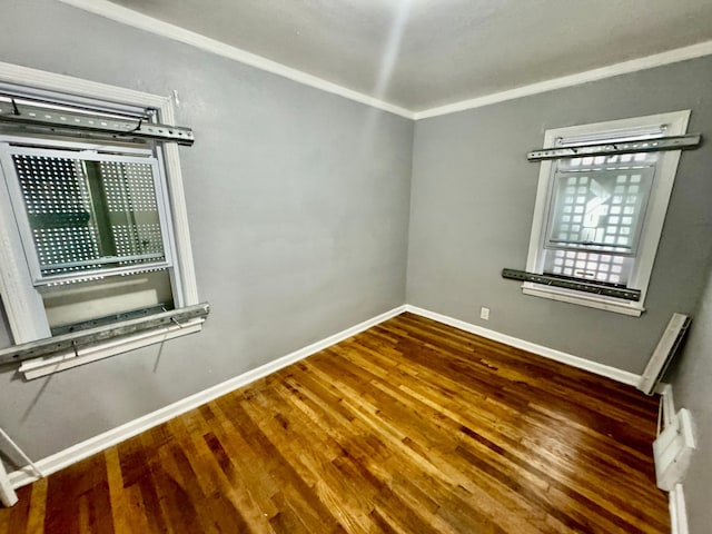 empty room featuring crown molding and hardwood / wood-style flooring