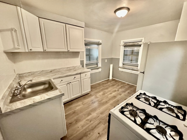 kitchen featuring tasteful backsplash, white cabinetry, sink, white appliances, and light hardwood / wood-style flooring