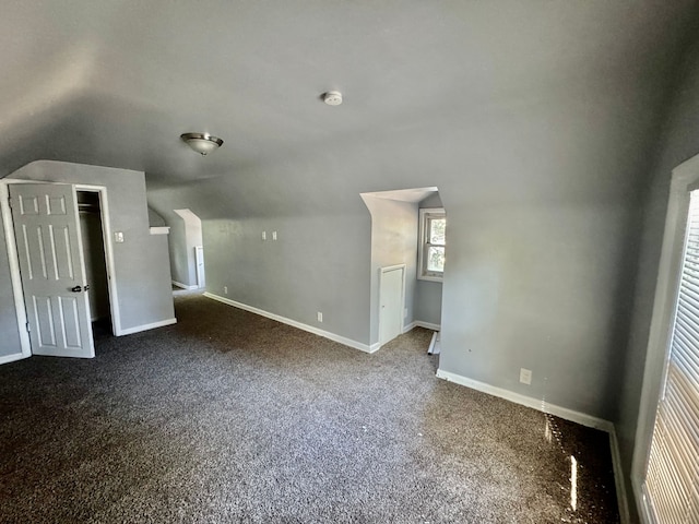 bonus room featuring lofted ceiling and dark carpet