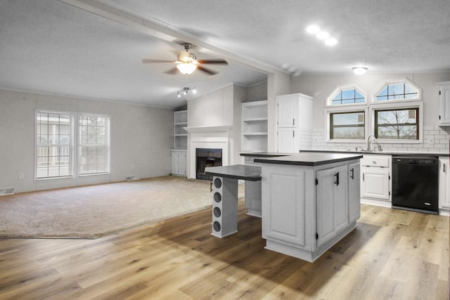 kitchen featuring lofted ceiling, a center island, light hardwood / wood-style flooring, black dishwasher, and white cabinets