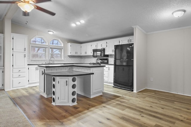 kitchen featuring white cabinets, lofted ceiling, a kitchen island, and black appliances