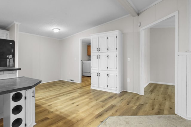 kitchen featuring washer / dryer, white cabinetry, black fridge, ornamental molding, and light hardwood / wood-style floors