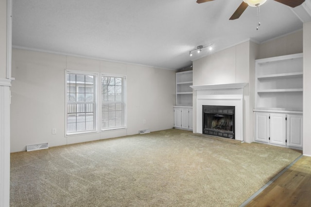 unfurnished living room with lofted ceiling, carpet floors, ceiling fan, and built in shelves