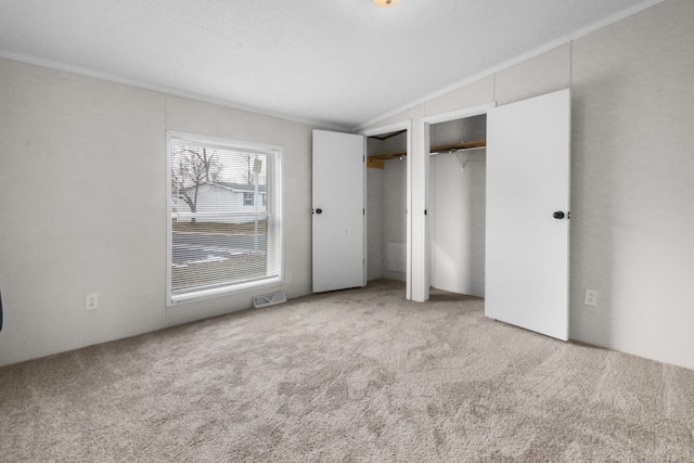 unfurnished bedroom with multiple closets, light colored carpet, and lofted ceiling