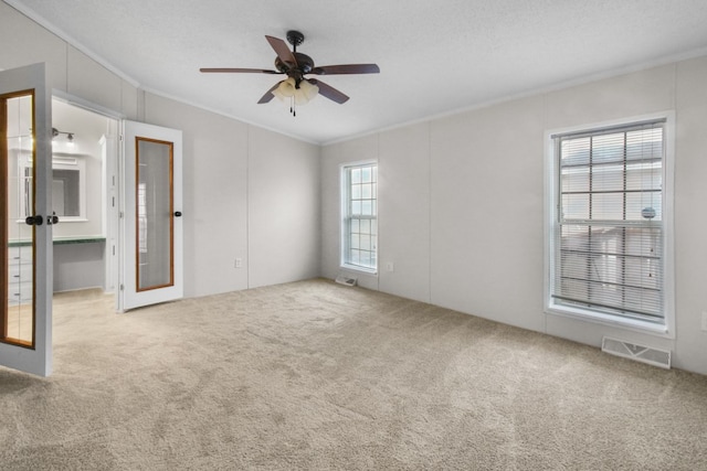 unfurnished room featuring crown molding, ceiling fan, carpet floors, a textured ceiling, and french doors