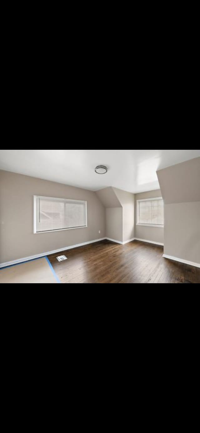 additional living space featuring dark hardwood / wood-style floors and vaulted ceiling