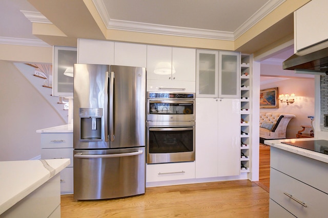 kitchen with crown molding, light wood-type flooring, white cabinets, and appliances with stainless steel finishes