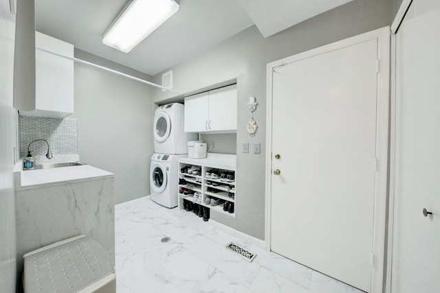 washroom with sink, cabinets, and stacked washer and clothes dryer