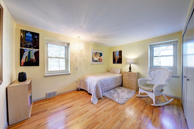 bedroom featuring multiple windows, a chandelier, and light hardwood / wood-style flooring