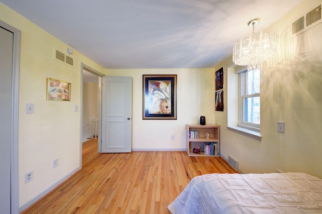 bedroom with an inviting chandelier and light hardwood / wood-style floors