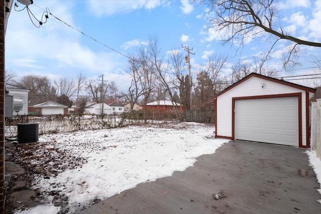 snowy yard with a garage, an outdoor structure, and central air condition unit