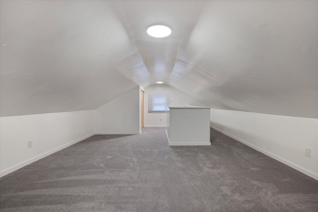 bonus room with lofted ceiling and dark colored carpet