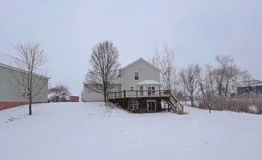 snow covered rear of property with a deck