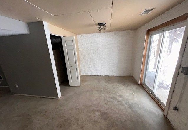 empty room featuring brick wall and concrete floors