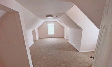 bonus room with light carpet and lofted ceiling