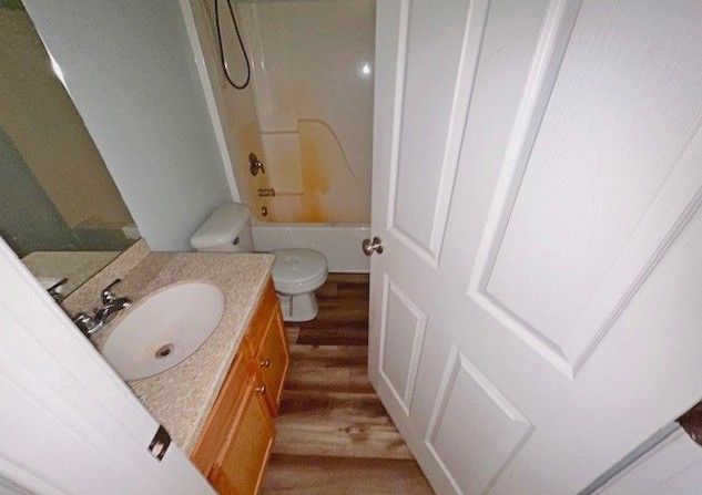 full bathroom featuring vanity, shower / washtub combination, hardwood / wood-style floors, and toilet