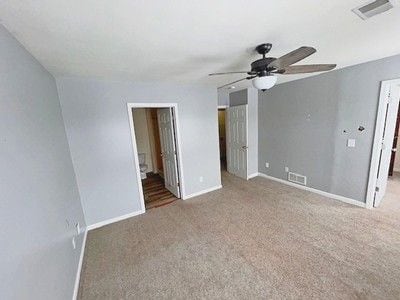 unfurnished bedroom featuring ensuite bathroom, carpet, a spacious closet, and ceiling fan