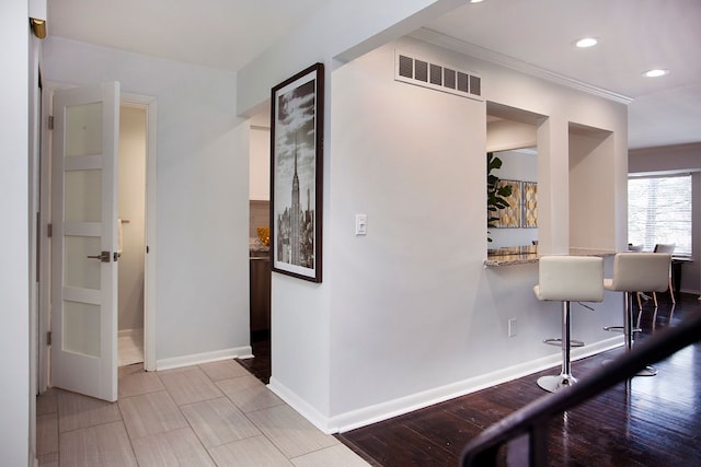 hallway with ornamental molding and light hardwood / wood-style floors