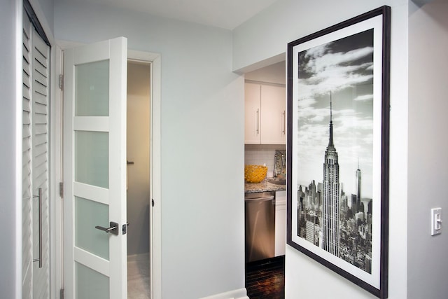 bar featuring sink, tasteful backsplash, white cabinetry, stainless steel dishwasher, and dark hardwood / wood-style floors