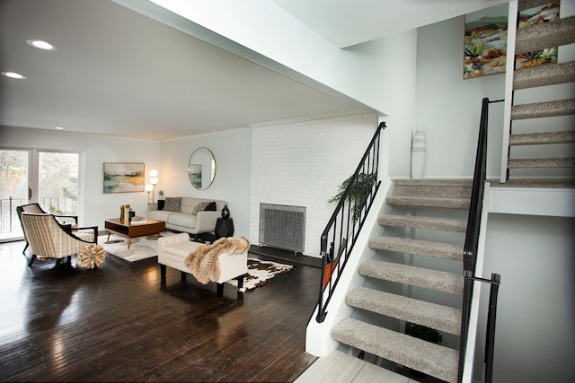 living room with a brick fireplace and wood-type flooring