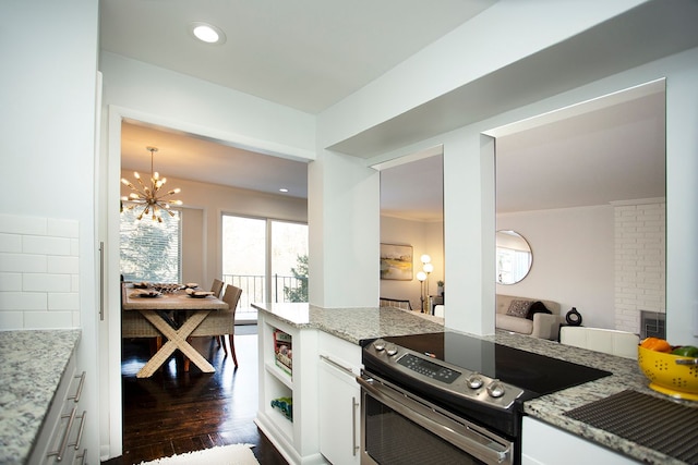 kitchen with stainless steel electric range, dark wood-type flooring, a notable chandelier, light stone countertops, and white cabinets