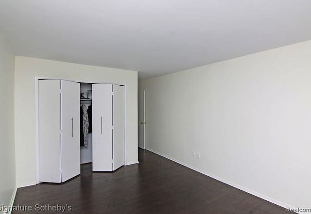 unfurnished bedroom with dark hardwood / wood-style flooring and a closet