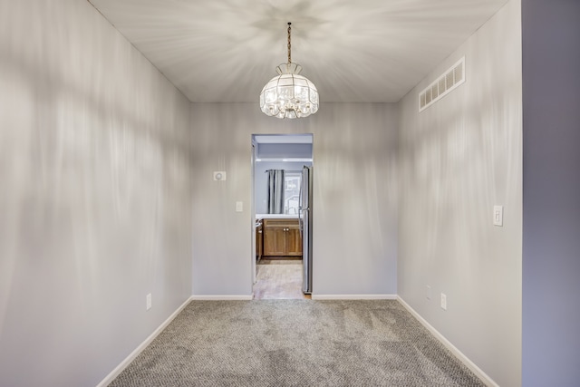 carpeted empty room featuring a chandelier