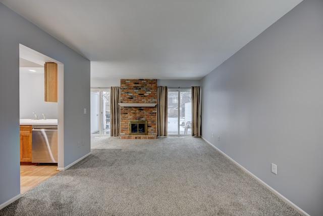 unfurnished living room featuring light colored carpet, a fireplace, and sink