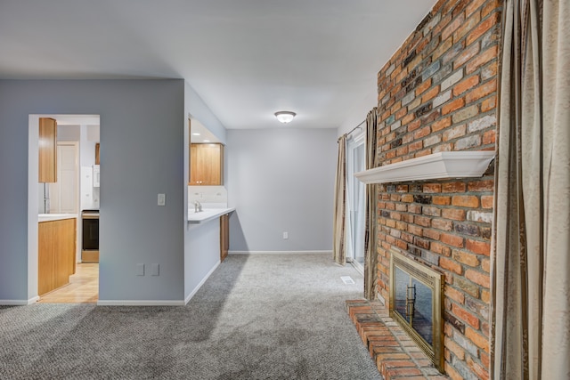 unfurnished living room with sink, light carpet, and a fireplace