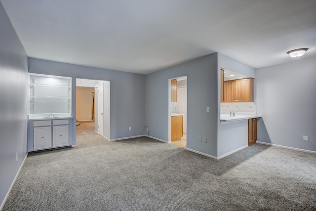 unfurnished living room with light colored carpet and sink