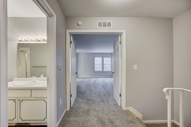 corridor featuring sink and light colored carpet