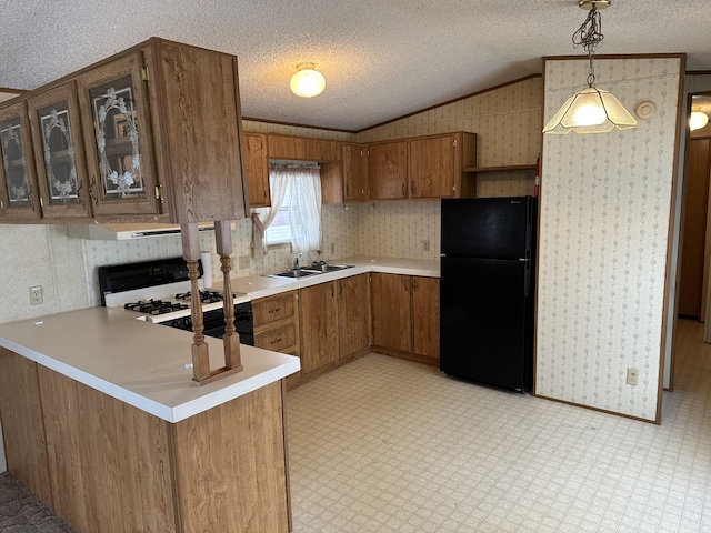 kitchen with black refrigerator, decorative light fixtures, sink, kitchen peninsula, and gas range oven