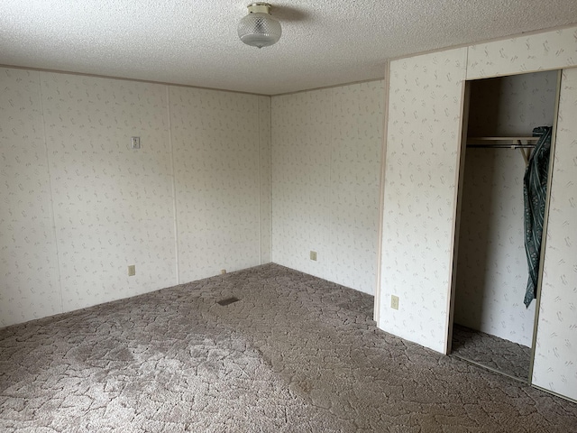 unfurnished bedroom featuring dark colored carpet, a textured ceiling, and a closet