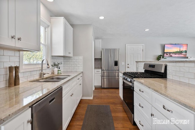 kitchen featuring stainless steel appliances, light stone countertops, sink, and white cabinets