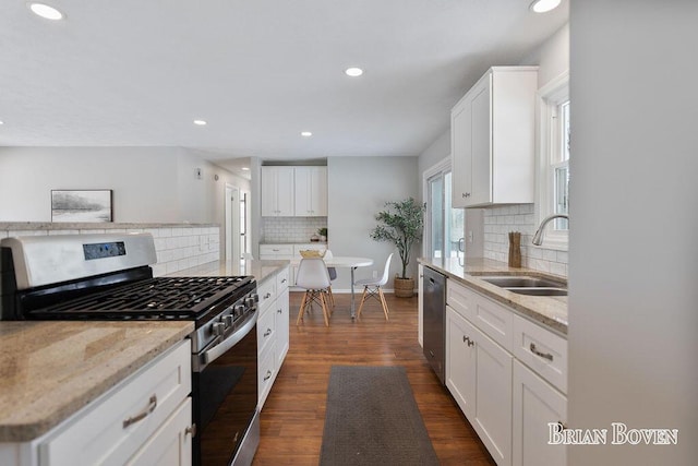 kitchen featuring dark wood-type flooring, sink, white cabinetry, stainless steel appliances, and light stone countertops