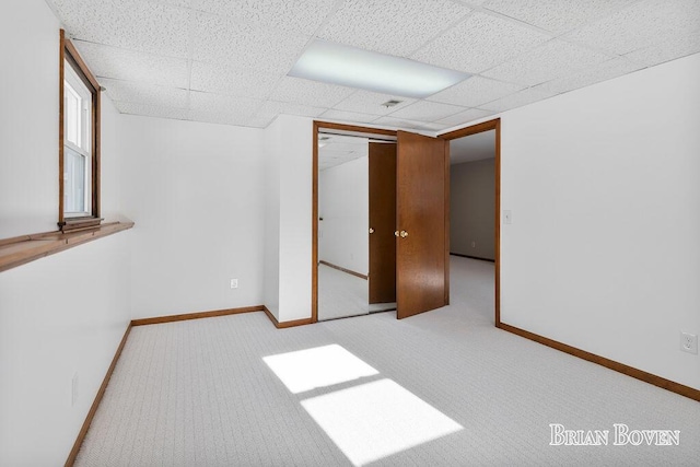 carpeted spare room featuring a drop ceiling