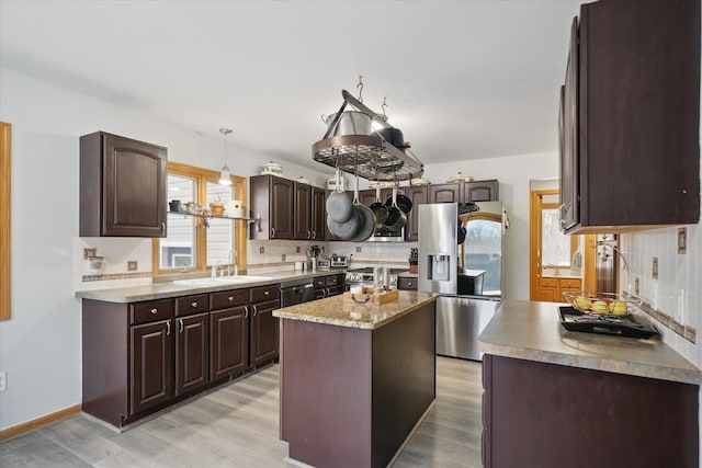 kitchen with sink, appliances with stainless steel finishes, dark brown cabinets, a center island, and decorative light fixtures