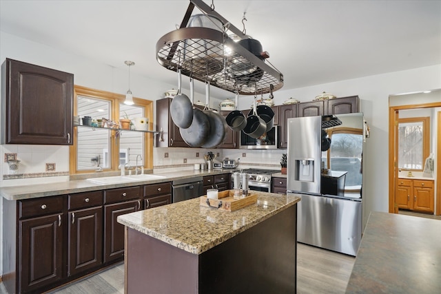 kitchen featuring stainless steel appliances, a kitchen island, plenty of natural light, and pendant lighting