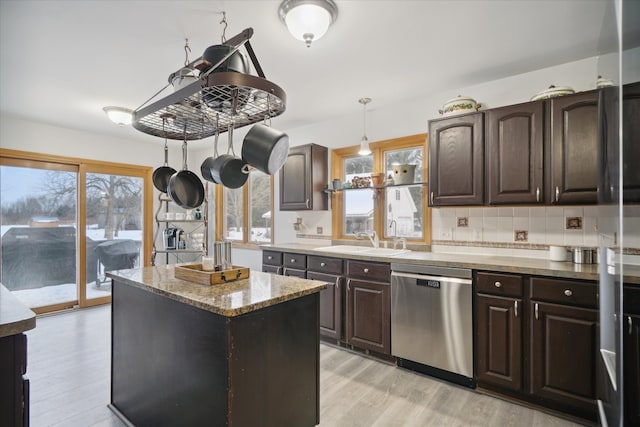 kitchen featuring pendant lighting, sink, dishwasher, dark brown cabinets, and light hardwood / wood-style floors