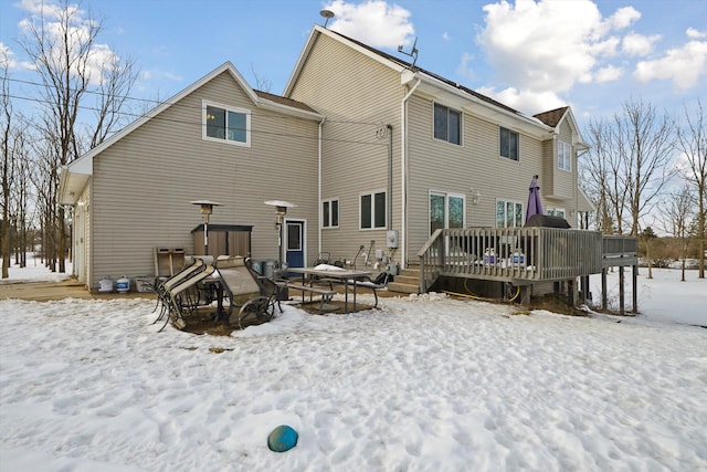 snow covered rear of property with a deck