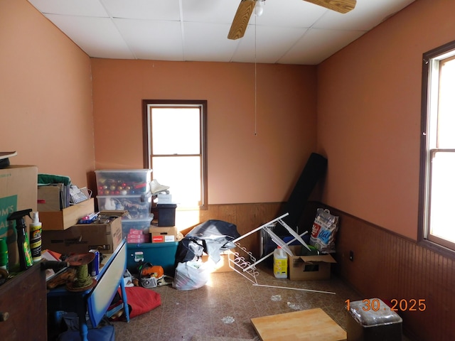 interior space featuring ceiling fan, a paneled ceiling, and wooden walls