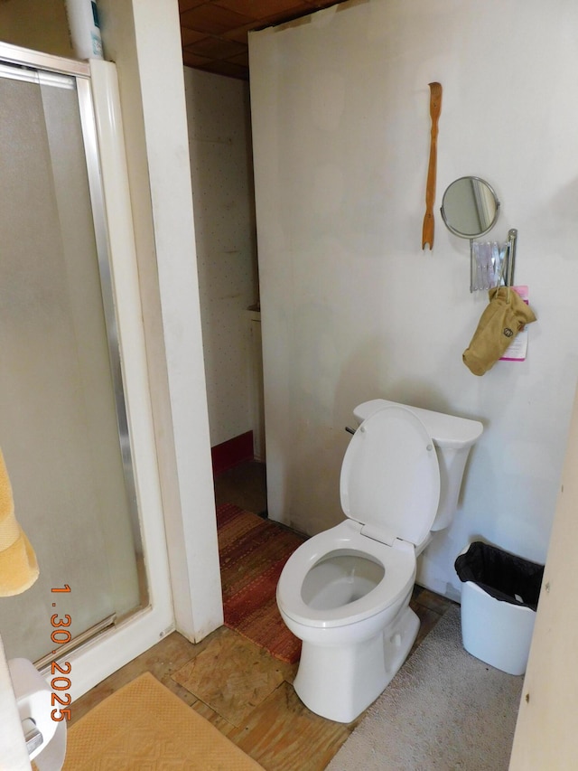 bathroom featuring a shower with door and toilet