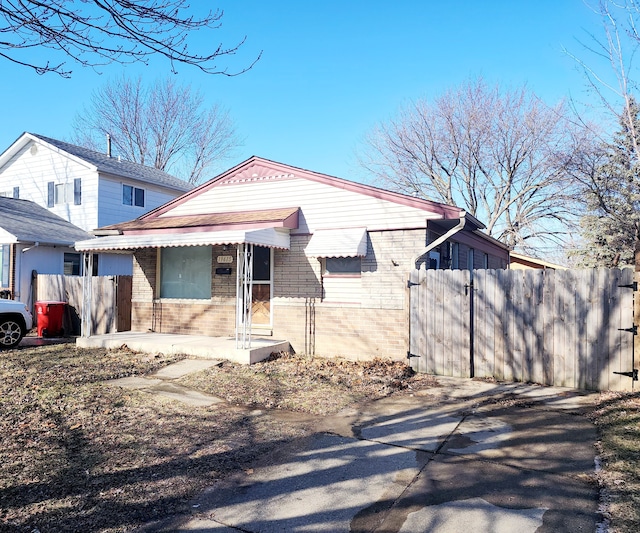 view of front of property with brick siding, fence, and a gate