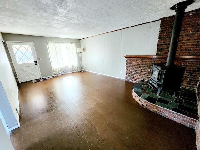 unfurnished living room featuring hardwood / wood-style floors, a textured ceiling, and a wood stove