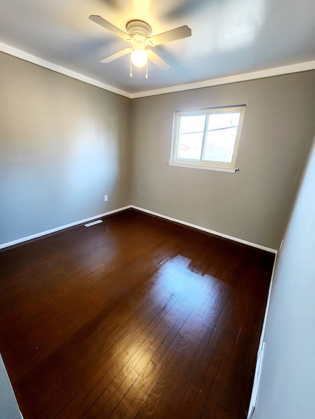 empty room featuring baseboards, dark wood finished floors, a ceiling fan, and ornamental molding