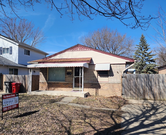 rear view of house with brick siding and fence