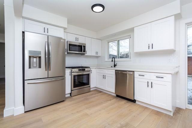 kitchen featuring stainless steel appliances, sink, white cabinets, and light hardwood / wood-style floors