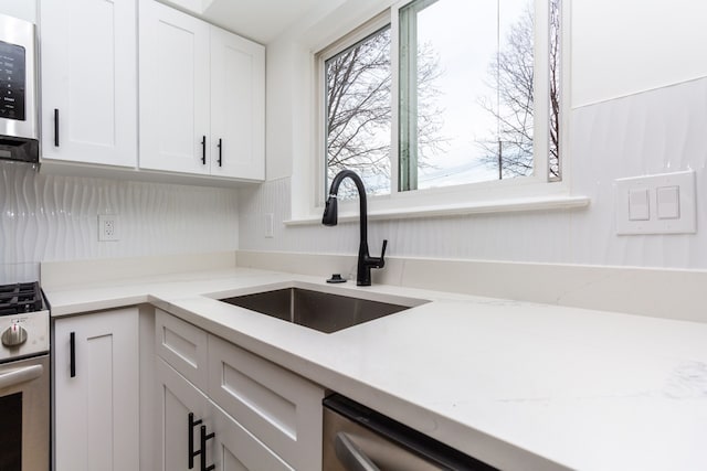 kitchen featuring white cabinetry, sink, light stone counters, and appliances with stainless steel finishes