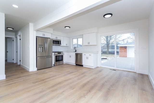 kitchen featuring white cabinetry, appliances with stainless steel finishes, sink, and light wood-type flooring