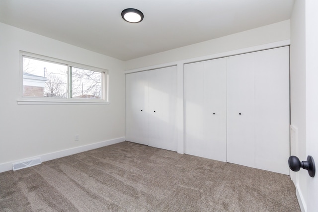 unfurnished bedroom featuring multiple closets and carpet